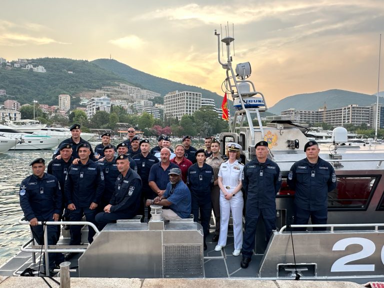 Group of uniformed Navy personnel standing on ship.